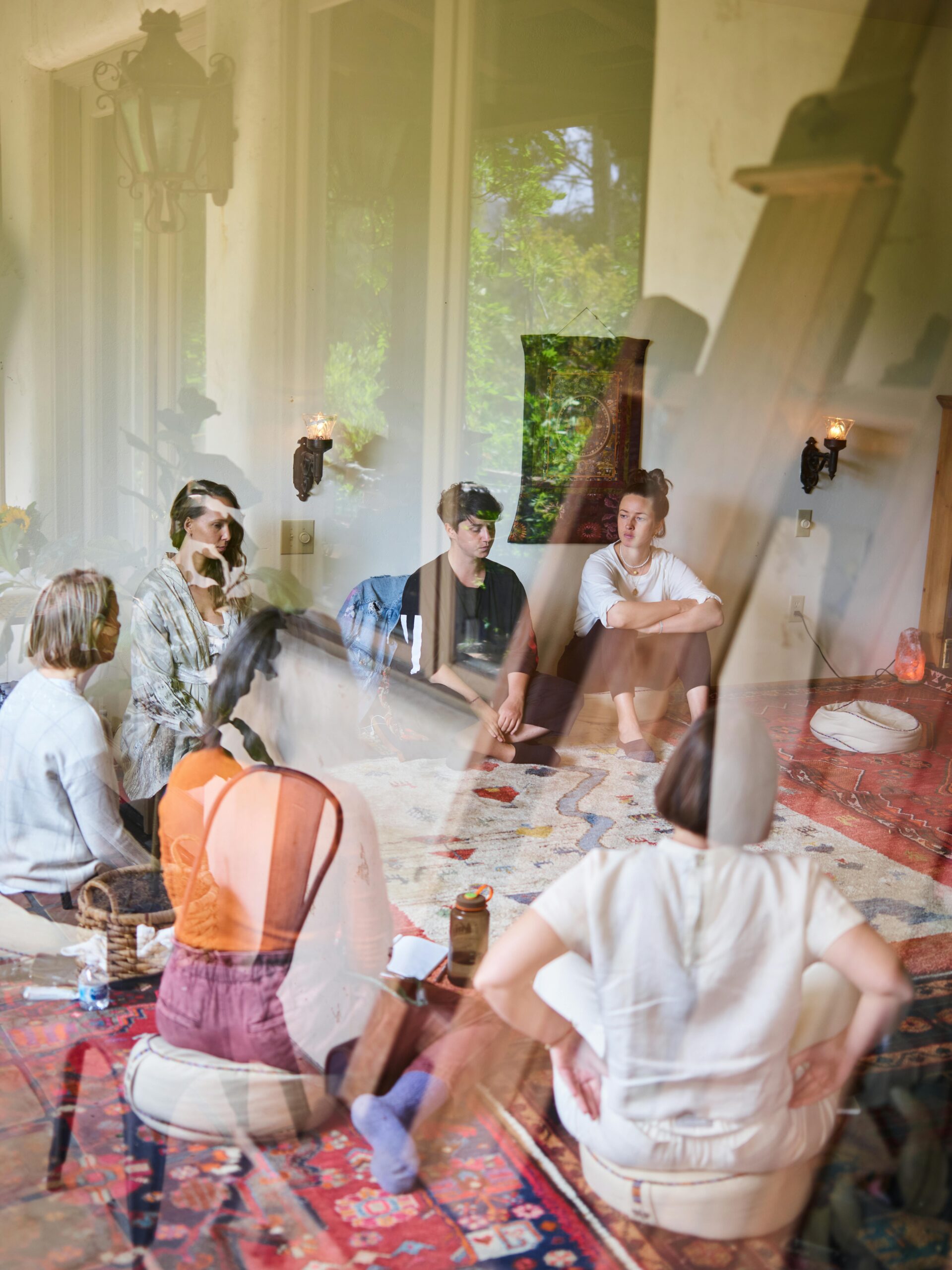 Esileht A diverse group sits in a circle during a relaxed meditation session indoors.